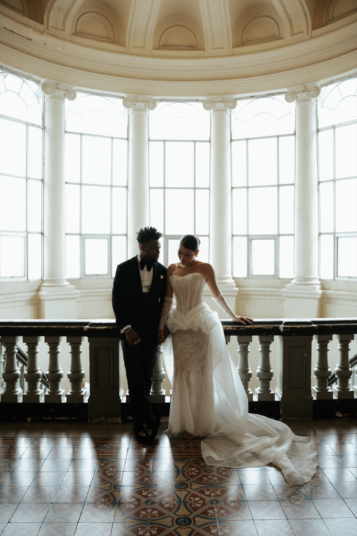 Chú rể mặc tuxedo bên cô dâu dưới mái vòm